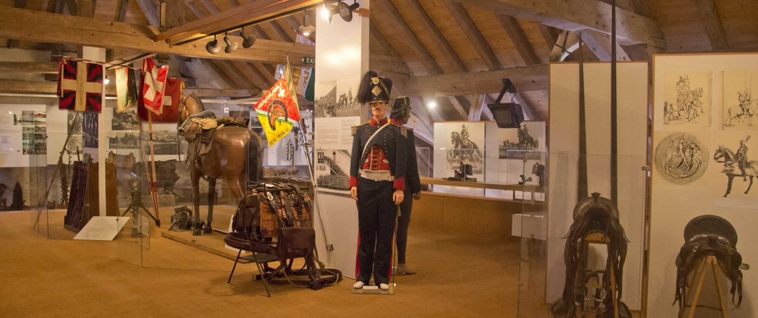 Salle "Le cheval dans l'armée" au Musée Suisse du Cheval, La Sarraz. Immersion dans l'histoire équestre et les métiers traditionnels. Exposition interactive sur le patrimoine artisanal lié au cheval. Ateliers ludiques au Château.